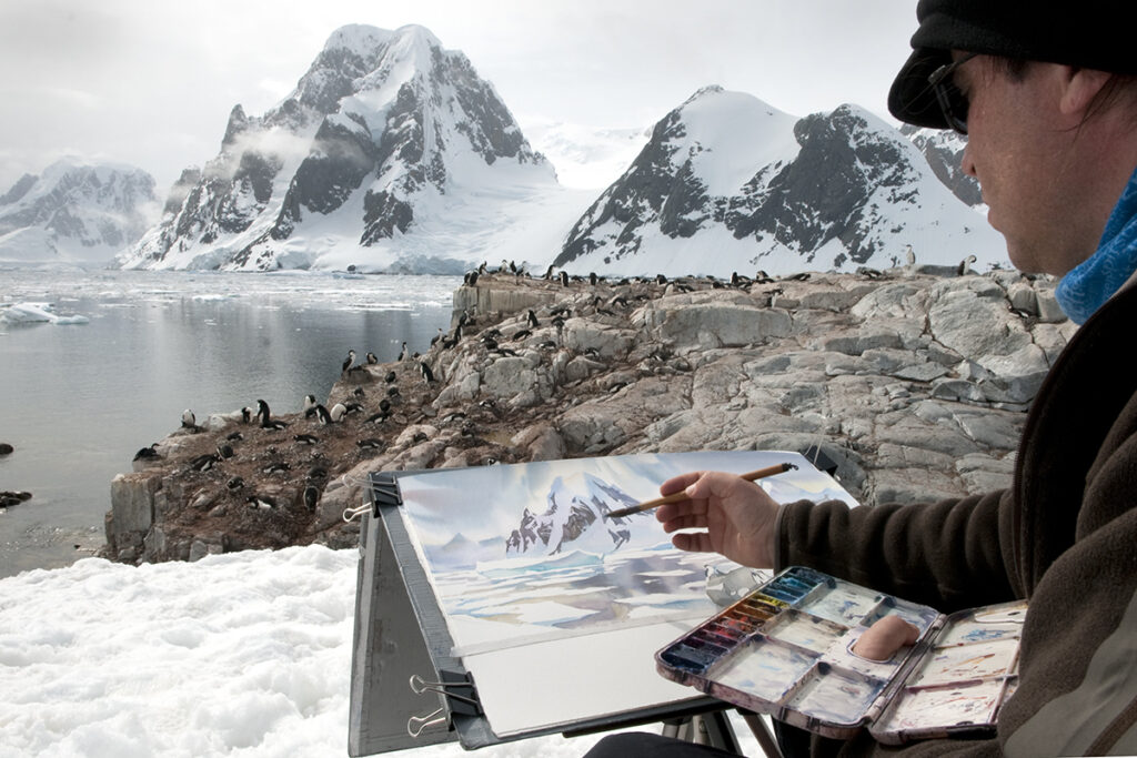 artist painting at his easel in front of icefields in Antarctica